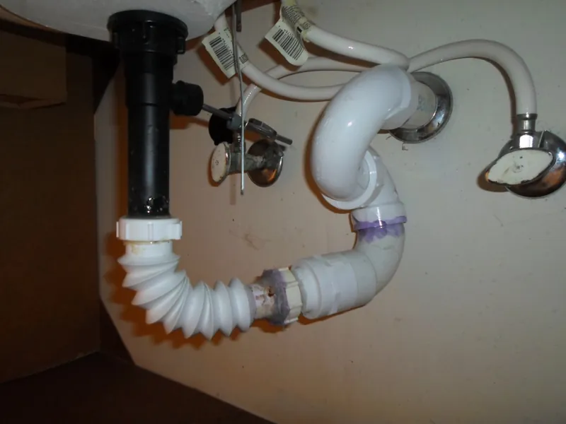 Drain plumbing under a sink photographed during an inspection