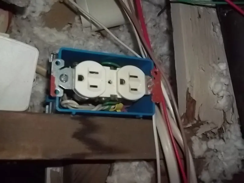 An electrical outlet buried in attic insulation