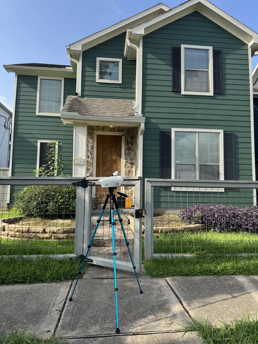 A new two-story Houston home with an A-Action inspection camera on a tripod at the front gate