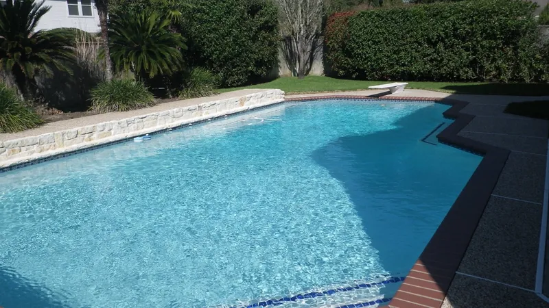 A large backyard swimming pool with a diving board at a Houston home