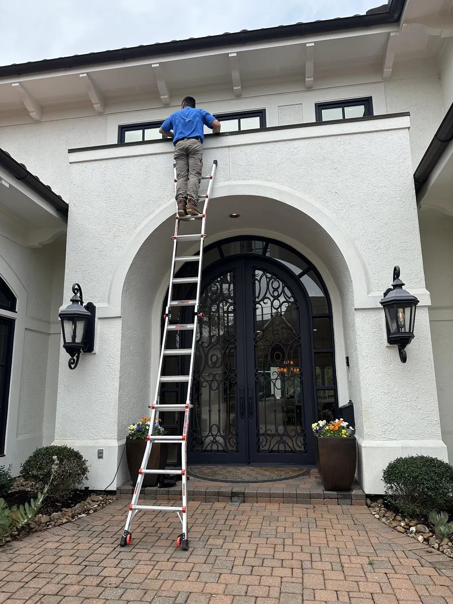 An A-Action inspector climbing a ladder to the roof of a new Houston home